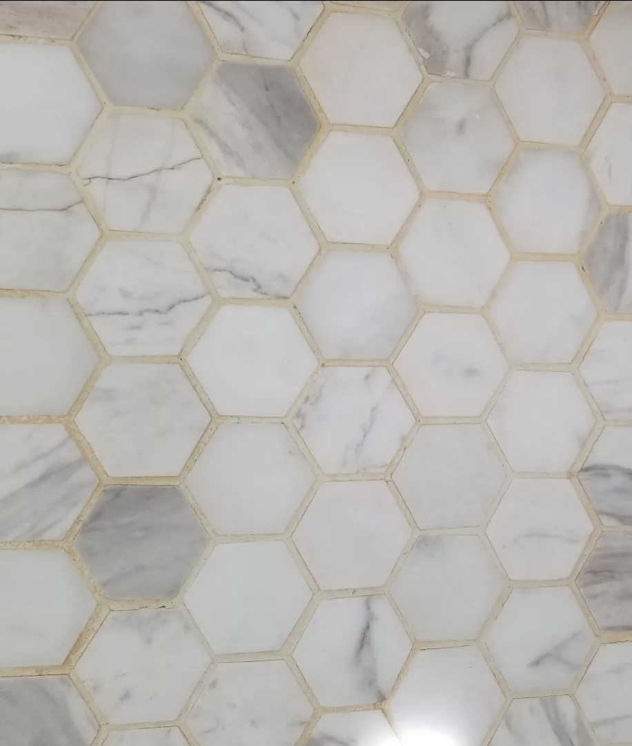 Hexagon marble tile floor with discolored grout before cleaning